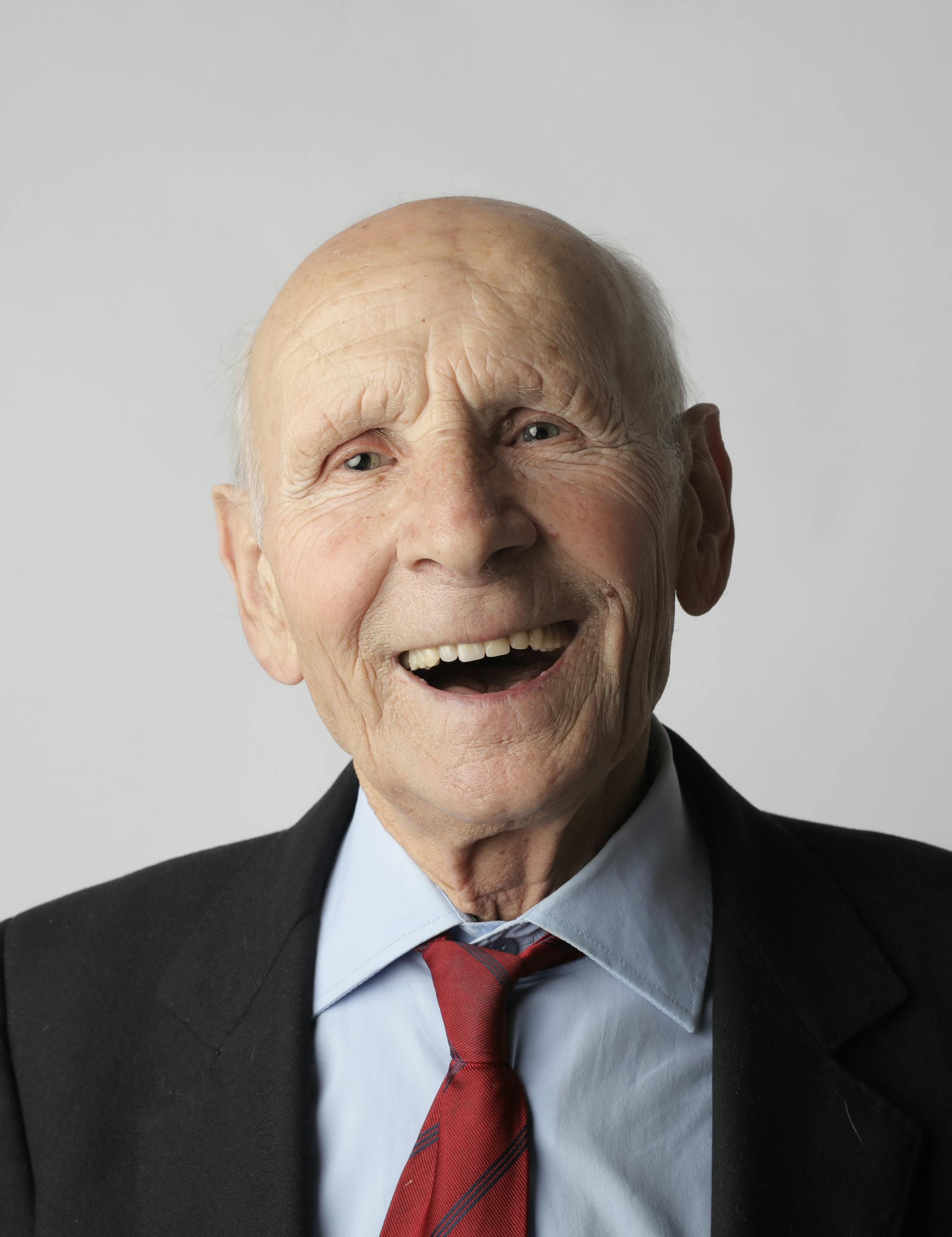 A smiling elderly man in a suit and tie, conveying happiness and wisdom.