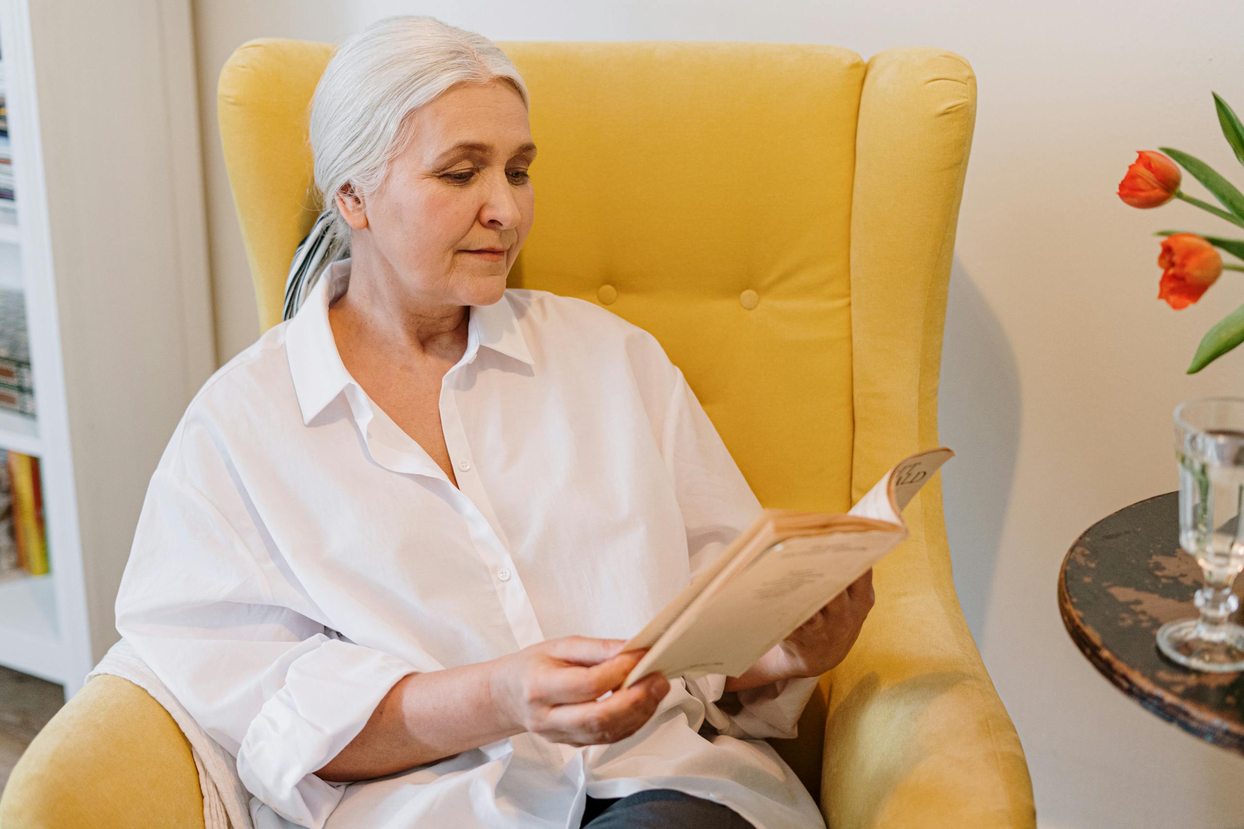 Senior woman enjoying a quiet reading moment in a cozy home with a warm atmosphere.