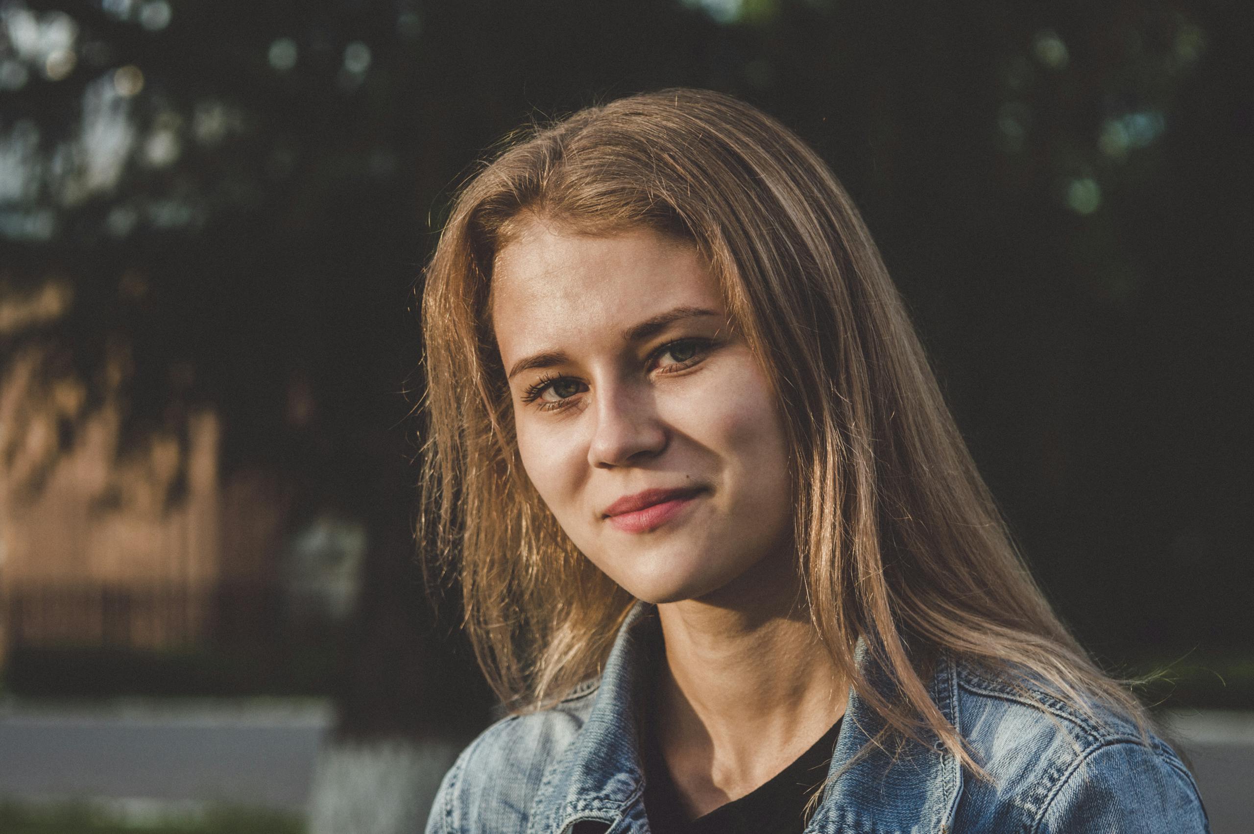 Smiling young woman in casual attire enjoying a sunny day in the park.