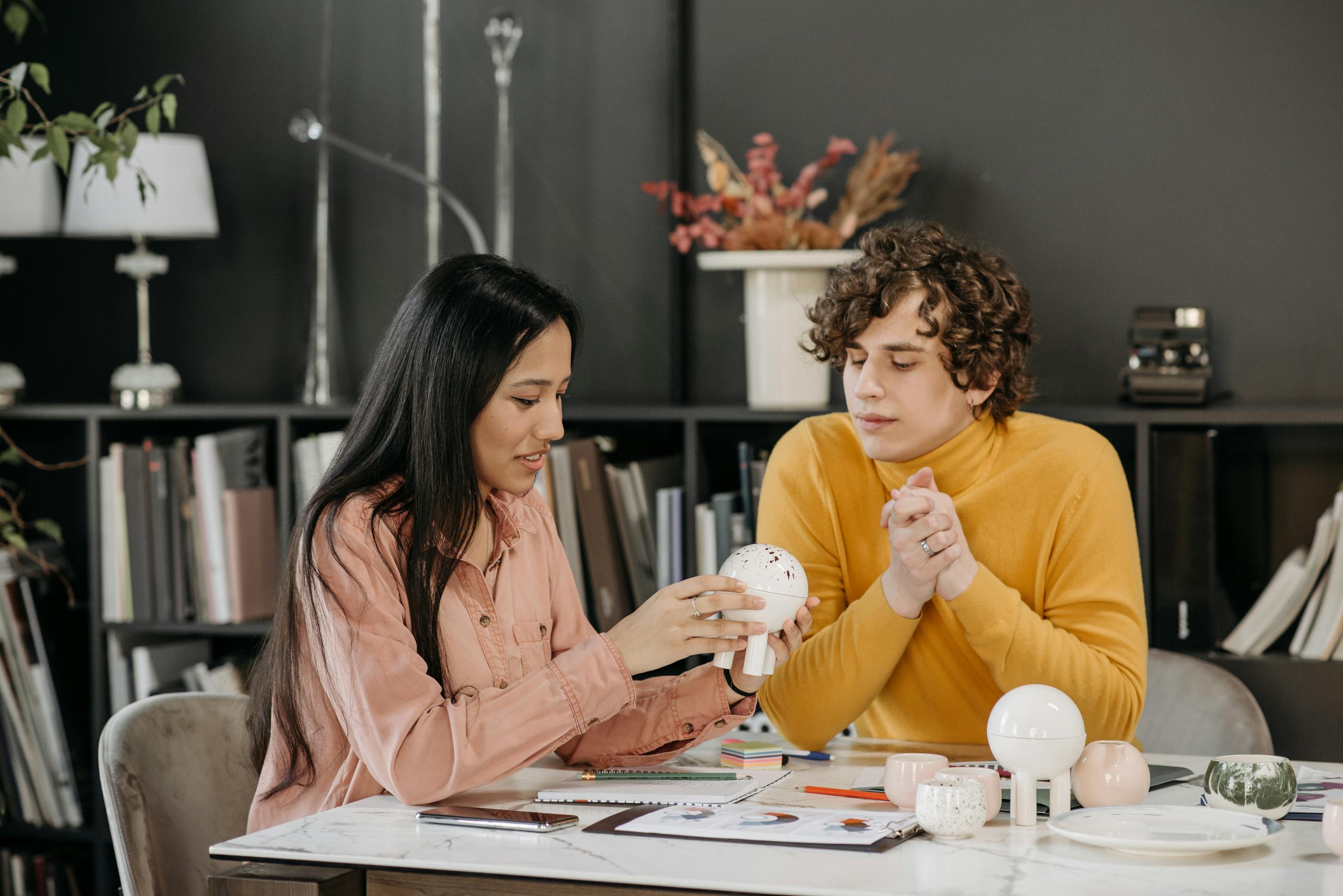 Young professionals discussing a project with ceramic models in a modern office setting.